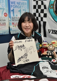 草創期以降のグッズを手に震災当時を振り返る今碇七重さん。Ｊリーグ昇格時に着ていたユニホーム姿でスタジアムに駆け付ける＝神戸市中央区東川崎町１（撮影・風斗雅博）