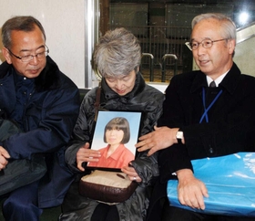 黒田裕子さんの遺影を持ち、臨時便の出発を待つ宇都（うと）幸子さん（中央）、高橋守雄さん（右）ら＝１７日午前４時１２分、神戸市西区糀台５、市営地下鉄西神中央駅