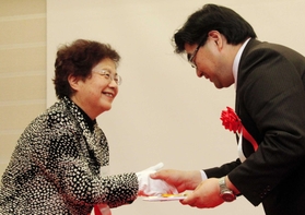 今年の竸基弘賞に輝いた研究者と握手する竸恵美子さん（左）＝神戸国際会議場