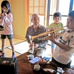 高須恒さんが見守る中、長男厚志さんのトランペットを吹き鳴らす孫たち＝静岡県磐田市気子島