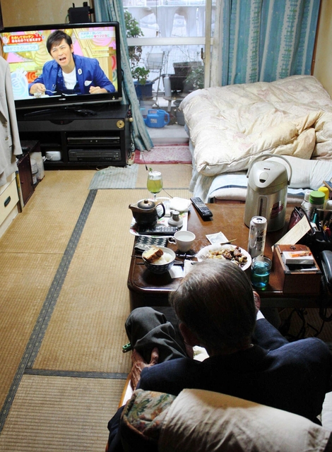 復興住宅の部屋でテレビを見つめる男性。ほとんど外に出ない＝神戸市長田区西尻池町１