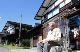 住み慣れた木造の復興住宅の前で、くつろぐ浅染五郎清さん＝新潟県長岡市山古志東竹沢