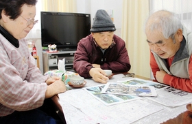 震災直後の写真を囲んで語り合う（左から）白井せつ子さん、政和さん、松山朝一さん＝神戸市長田区菅原通３