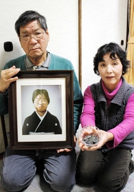 姉嘉子さんの遺影を持つ徳平克三さん（左）と、焦げた小銭を手にする妻多鶴さん＝神戸市須磨区東落合２