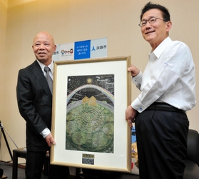 「神戸の壁」をテーマに描いた作品を門康彦淡路市長（右）に手渡す三原泰治さん＝淡路市役所