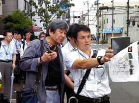 阪神・淡路大震災当時の被害を端末で確認しながらまちを歩く参加者＝神戸市兵庫区松本通