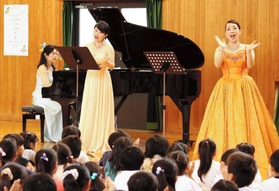 手拍子をしながらピアノの音色と歌声の美しいハーモニーを楽しむ児童ら＝糀台小学校