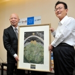「神戸の壁」をテーマに描いた作品を門康彦淡路市長（右）に手渡す三原泰治さん＝淡路市役所