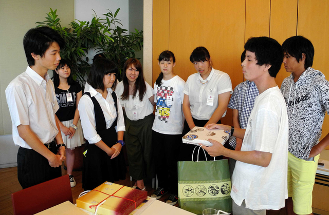 仙台二高の生徒に記念品をわたす兵庫高校の生徒（右）＝東京・汐留の共同通信社