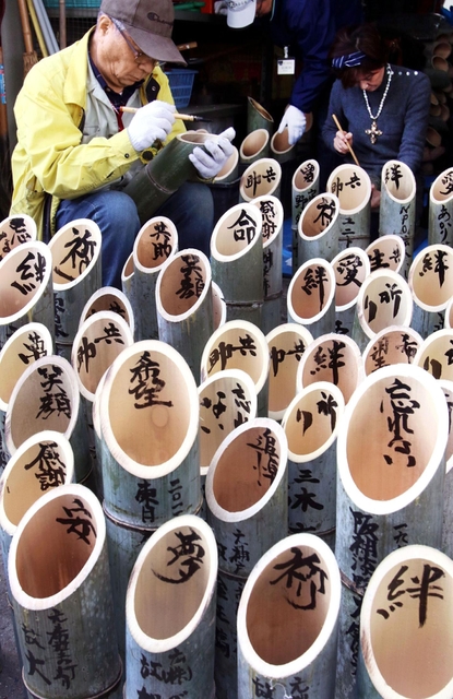 祈りを込め、竹灯籠に文字を書き入れる参加者たち＝６日午前、神戸市灘区（撮影・小林良多）