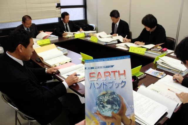 アース員向けのハンドブック（手前）の改訂を進めるメンバー＝兵庫県庁