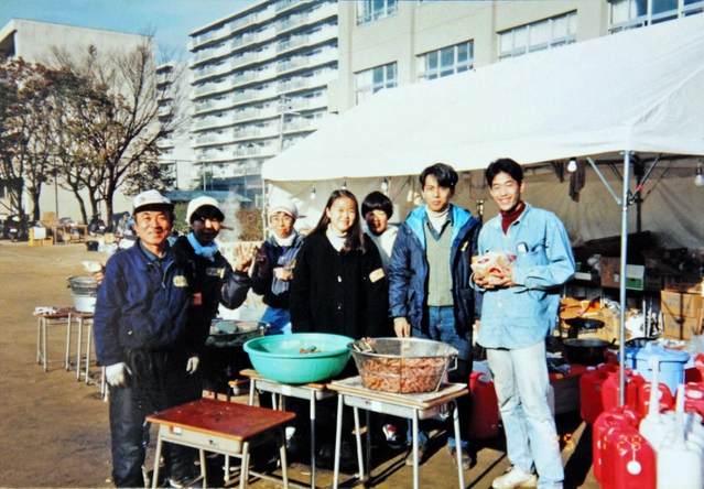 避難所のボランティアと写真に収まる深田勲さん（左端）＝１９９５年１月、本山南小学校（深田さん提供）