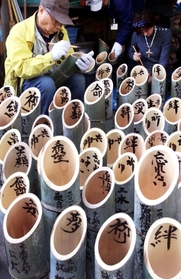 祈りを込め、竹灯籠に文字を書き入れる参加者たち＝６日午前、神戸市灘区（撮影・小林良多）