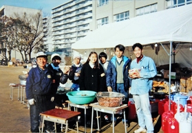 避難所のボランティアと写真に収まる深田勲さん（左端）＝１９９５年１月、本山南小学校（深田さん提供）