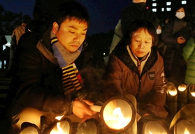 竹灯籠に火をともす松田一彦さん（左）と母信子さん＝１７日朝、東遊園地（撮影・大森　武）