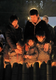 両親と弟、祖母を失った名城直樹さん（右上）は、妻千鶴さん、３人の子どもとともに竹灯籠の明かりを見つめた＝１７日朝、神戸市中央区の東遊園地