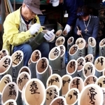 祈りを込め、竹灯籠に文字を書き入れる参加者たち＝６日午前、神戸市灘区（撮影・小林良多）