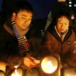 竹灯籠に火をともす松田一彦さん（左）と母信子さん＝１７日朝、東遊園地（撮影・大森　武）