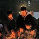 両親と弟、祖母を失った名城直樹さん（右上）は、妻千鶴さん、３人の子どもとともに竹灯籠の明かりを見つめた＝１７日朝、神戸市中央区の東遊園地