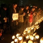 震災２１年を迎え、竹灯籠を前に黙とうする人たち＝１７日午前５時４６分、東遊園地（撮影・大森　武）