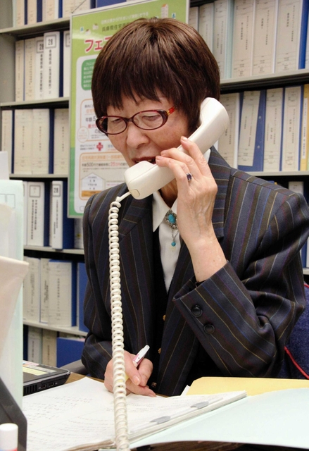 県外被災者に電話をする岡部育子さん＝兵庫県庁