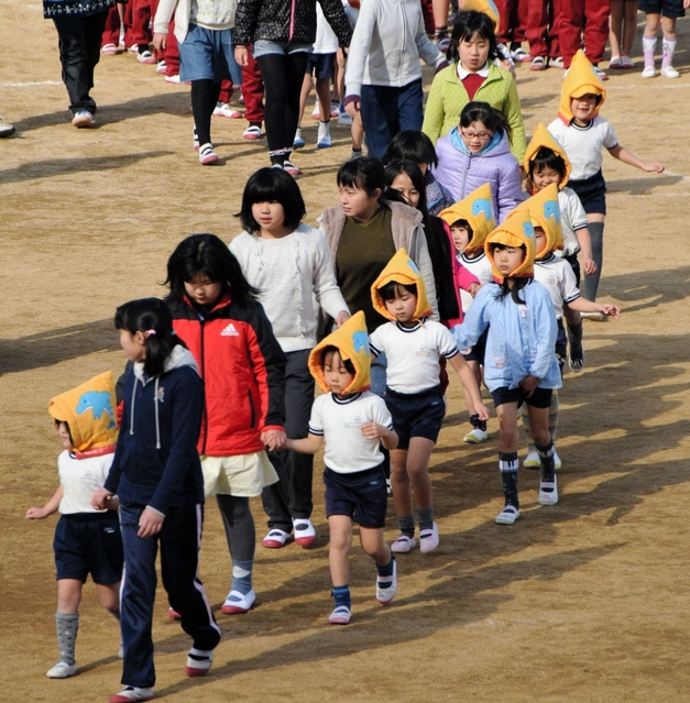 幼稚園児と手をつないで避難する児童たち＝洲本市、洲本第三小学校