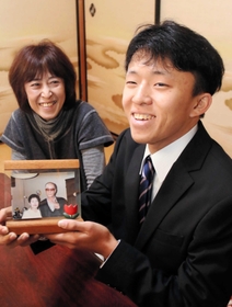 祖父母の写真を手に、母さゆりさん（左）から成人を祝われる小我野良介さん＝篠山市今田町下小野原