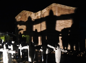 人影の十字架が浮かび上がった「神戸の壁」＝８日夜、北淡震災記念公園