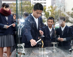 「希望の灯り」の火を持ち寄ったランタンに移す中学生ら＝９日午後、神戸市中央区、東遊園地