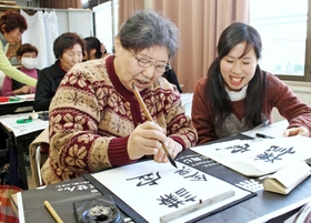 今年最初の授業は習字。丁寧に筆を運ぶ参加者をスタッフが見守る＝神戸市長田区
