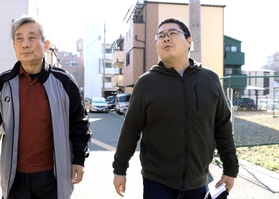 震災の語り部活動を始める柴田大輔さん（右）。語り部グループの崔敏夫さんと、今も更地が残る被災地を歩く＝神戸市須磨区千歳町１（撮影・小林良多）