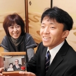 祖父母の写真を手に、母さゆりさん（左）から成人を祝われる小我野良介さん＝篠山市今田町下小野原