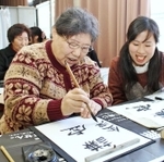今年最初の授業は習字。丁寧に筆を運ぶ参加者をスタッフが見守る＝神戸市長田区