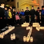 「２２」「１・１７」の文字をかたどったろうそくを囲み、黙祷をささげる住民ら＝淡路市郡家