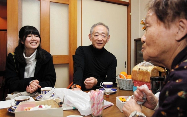 復興住宅で暮らす女性（右）の自宅を訪れ、語り合う牧秀一さん（中央）ら＝神戸市灘区内