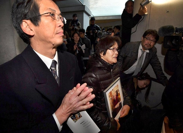 立花武さんの遺影を抱く妻の由紀恵さん（中央）と、銘板に手を合わせる長男の隆さん（左）＝神戸市中央区加納町６（代表撮影）