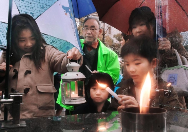 「１・１７希望の灯り」から火を移す子どもたち＝８日午後、神戸市中央区加納町６（撮影・吉田敦史）