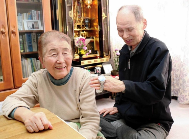 長男伸也さんの形見の時計を見ながら語り合う足立悦夫さん、朝子さん＝豊岡市塩津町