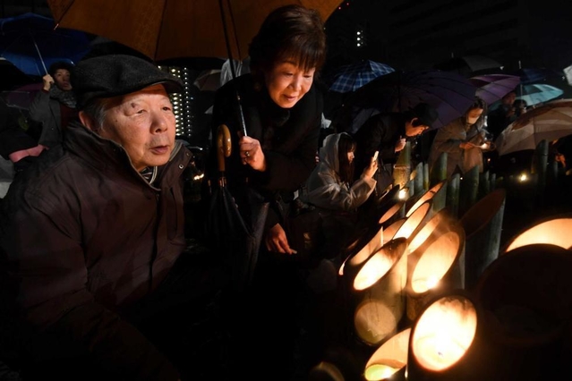 長男茂晴さんを思い、明かりのともった竹灯籠に語り掛ける稲見登さんと育子さん＝１７日午前５時５１分、神戸市中央区加納町６（撮影・中西大二）
