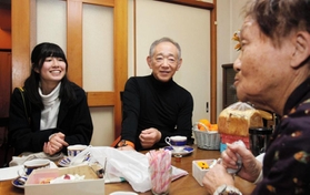 復興住宅で暮らす女性（右）の自宅を訪れ、語り合う牧秀一さん（中央）ら＝神戸市灘区内