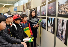 震災の発生直後から復興までのあゆみを紹介する写真に見入る小学生＝人と防災未来センター