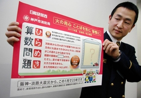 防災啓発メッセージが入ったポスターを広げる高岡消防司令補＝神戸市消防局