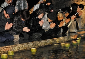 流れる灯籠に向かって手を合わせる遺族ら＝17日午前５時44分、淡路市小倉（撮影・内田世紀）