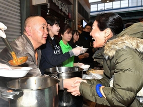 握手をしながら炊きだしのカレーを振る舞うタレント松村邦洋さん（左端）。コウベリーズのメンバーも手伝った＝神戸市長田区大橋町５（撮影・風斗雅博）