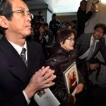 立花武さんの遺影を抱く妻の由紀恵さん（中央）と、銘板に手を合わせる長男の隆さん（左）＝神戸市中央区加納町６（代表撮影）
