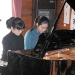 震災１０年のつどいで連弾する松本さん（右）と田中さん＝２００５年１月（浜風の家提供）
