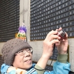 父の名前が刻まれた銘板にカメラを向ける本美穂子さん＝東遊園地（撮影・大森　武）