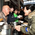 握手をしながら炊きだしのカレーを振る舞うタレント松村邦洋さん（左端）。コウベリーズのメンバーも手伝った＝神戸市長田区大橋町５（撮影・風斗雅博）