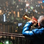 雨の中、神戸の街へ思いを込めて演奏するトランペット奏者松平晃さん（７６）＝２０１８年１月１７日、神戸市中央区神戸港地方、ビーナスブリッジ（撮影・田中靖浩）
