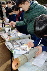 竹灯籠に筆で文字を書き込む中学生たち＝神戸市北区山田町